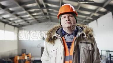 戴着安全帽、穿着工作服的人正站在机库的中间，双手放在摄像机的胸前